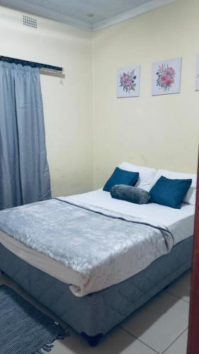 a bedroom with a bed with blue pillows at ZK Guesthouse in Manzini