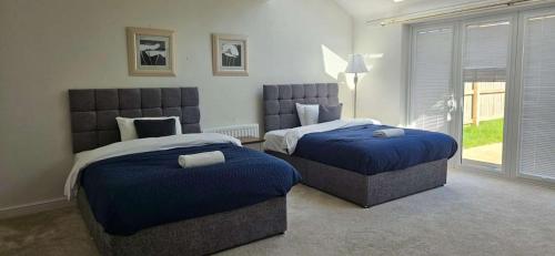 een slaapkamer met twee bedden met blauwe dekens en een raam bij Spacious Luxurious Serviced Accommodation 7 in Preston
