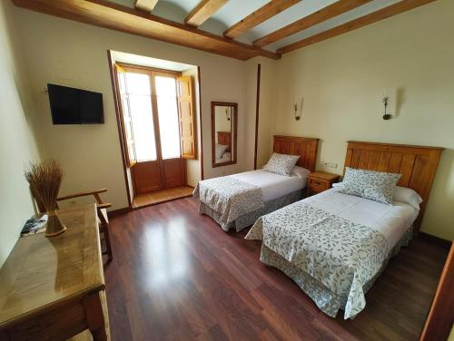 a room with two beds and a television in a room at HOTEL EL RASTRO - Palacio Duque de Tamames - in Avila