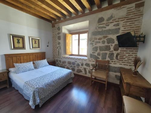 a bedroom with a bed and a stone wall at HOTEL EL RASTRO - Palacio Duque de Tamames - in Avila