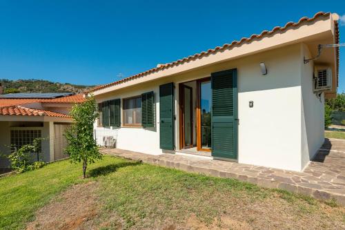 a house with green shutters and a yard at Villa Pilato in Poggio Dei Pini