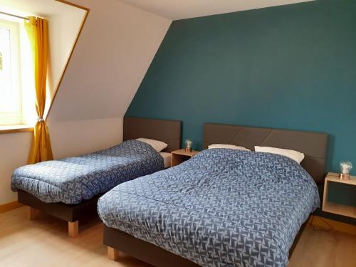 two beds in a bedroom with blue walls and a window at Chez le Bessou 