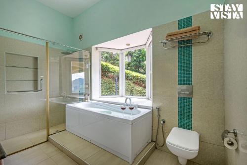 a bathroom with a tub and a toilet and a window at StayVista at Farview Suite Serenity with Lawn in Kotagiri