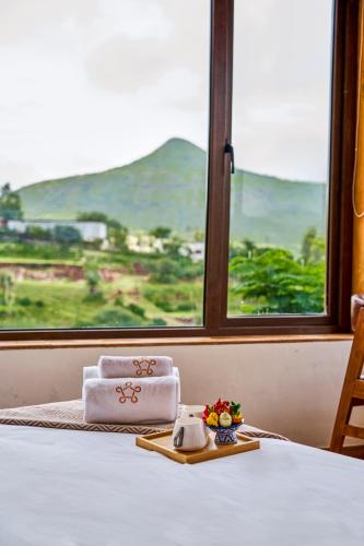 una mesa con una toalla y un plato de comida. en SaffronStays Aamelia by the Hills, en Trimbak
