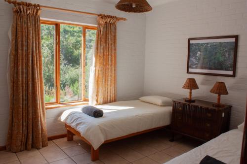 a bedroom with a bed and a window at Yellowwood Place in Bettyʼs Bay