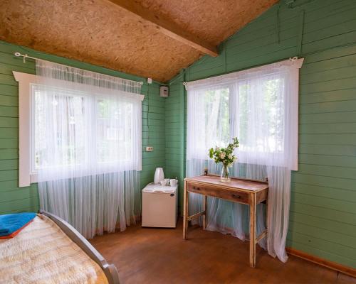 a green room with a table and two windows at Slėnis Trakuose in Trakai