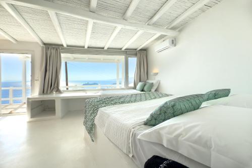 a bedroom with two beds and a large window at Eagles Nest Mykonos in Tourlos