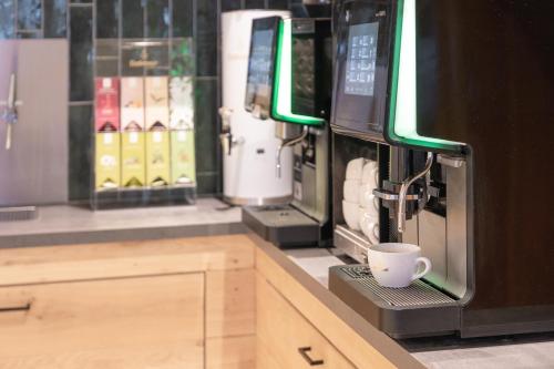 a coffee machine with a cup on a counter at Alpenhotel Tirolerhof Gerlos in Gerlos