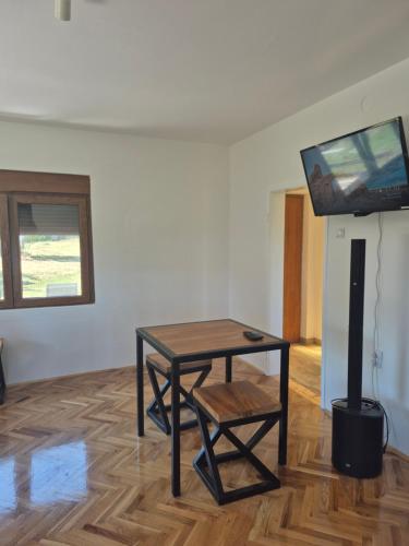 a room with a table and a tv on a wall at Domacinstvo Pecina Petnica in Petnica