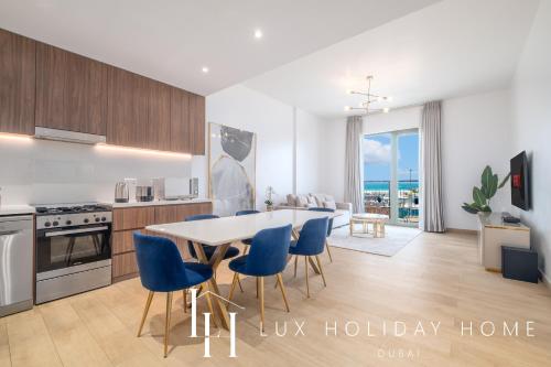 a kitchen and dining room with a table and blue chairs at LUX - The La Mer Sea View Suite 3 in Dubai