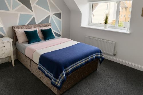 a bedroom with a bed with blue pillows and a window at Ensuite Private Cosy Space Near the Bus Station in Broughton