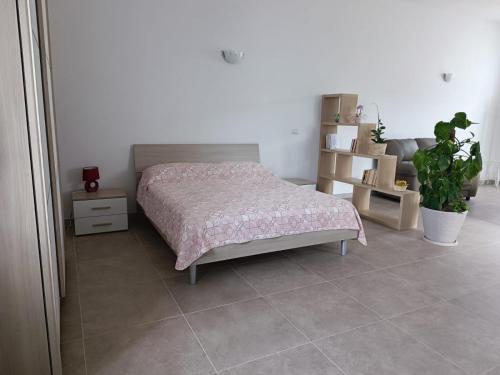 a bedroom with a bed and a potted plant at Casetta Girasole in Lamie di Olimpia