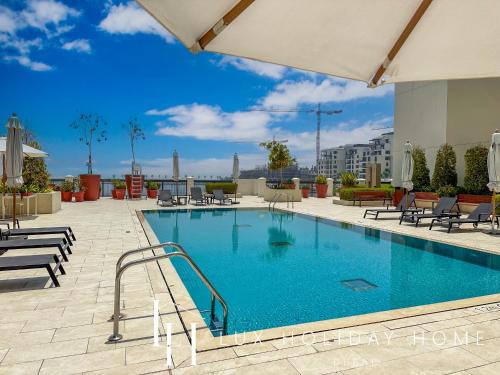 a swimming pool at a hotel with tables and chairs at LUX - The La Mer Sea View Suite 3 in Dubai