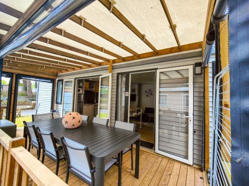 a dining room with a table and chairs on a deck at Mobilhome 6p camping le bois dormant in Quend-Plage