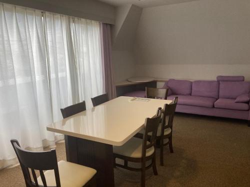a living room with a table and a purple couch at J-Hoppers Beppu Guesthouse ジェイホッパーズ別府ゲストハウス in Beppu