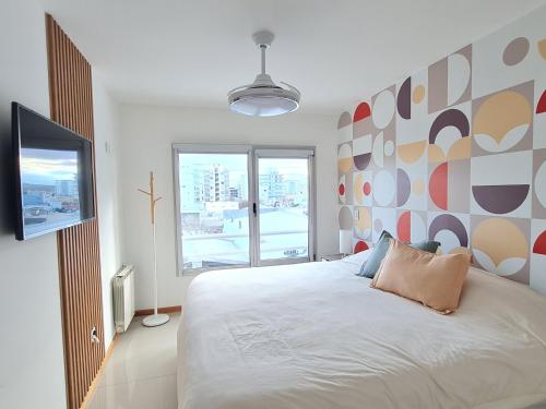 een slaapkamer met een bed en een groot raam bij AC Suites XL in Puerto Madryn