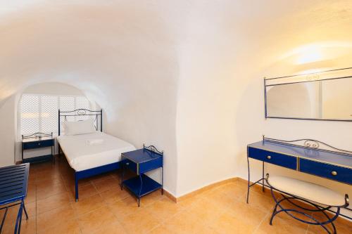 a room with a bed and a desk and a mirror at Kastro Suites in Fira
