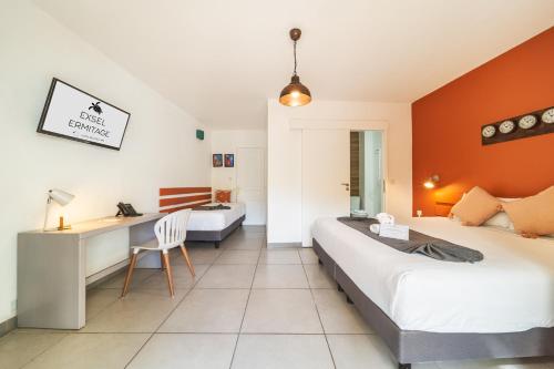a hotel room with two beds and a desk at Hôtel Exsel Ermitage in Saint-Gilles les Bains