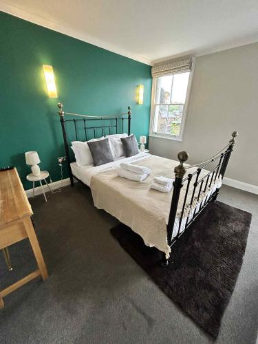 a bedroom with a bed and a green wall at Orla Restaurant & Rooms in Lindfield