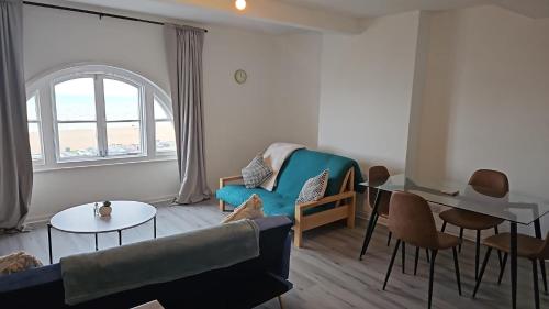 a living room with a blue couch and a table at Sea view two bedroom apartment in Hastings