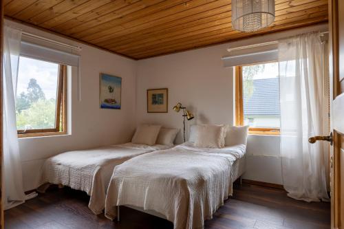 two beds in a room with two windows at Scenic Lakehouse near Stockholm with Sauna & Jetty in Huddinge