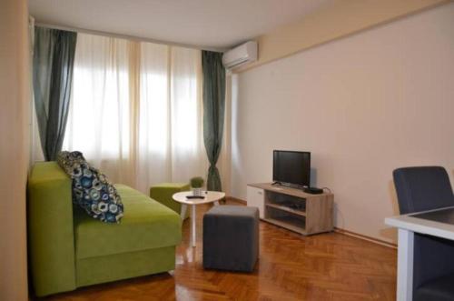 a living room with a green couch and a television at Apartments Sat in Belgrade