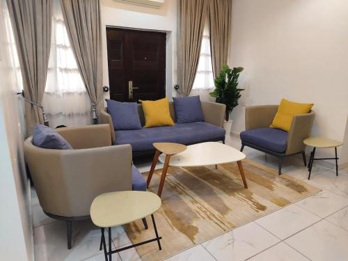 a living room with a blue couch and two chairs at Keev Homes Comfy 4bedroom duplex in Port Harcourt