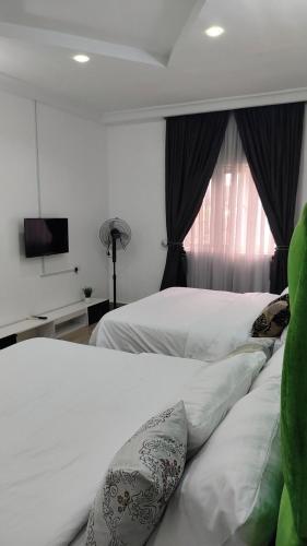 a bedroom with a bed with white sheets and a window at Keev Homes Comfy 4bedroom duplex in Port Harcourt