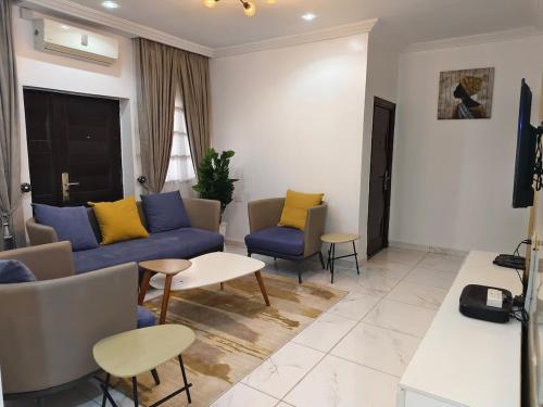 a living room with a blue couch and yellow pillows at Keev Homes Comfy 4bedroom duplex in Port Harcourt