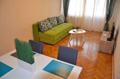 a living room with a green couch and a table at Apartments Sat in Belgrade