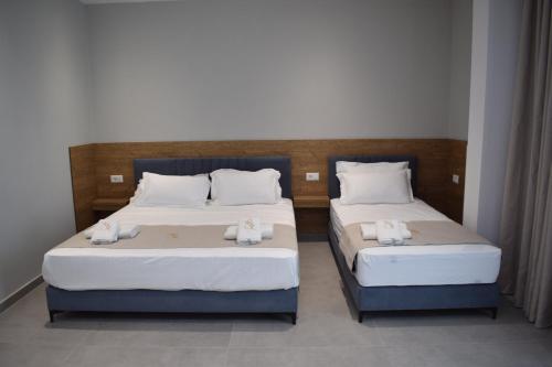 two beds in a room with towels on them at Hotel Sisana in Vlorë