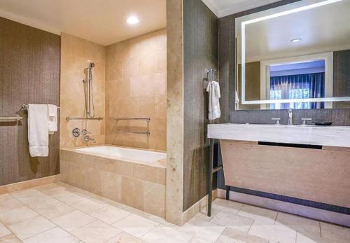 Un baño con bañera, lavabo y espejo. en Hotel Amarano Burbank-Hollywood, en Burbank