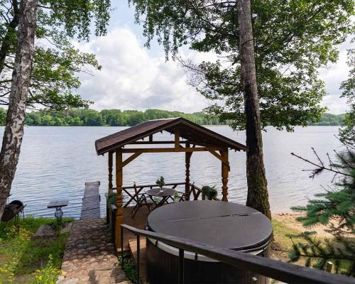 a gazebo with a table and a picnic table next to a lake at Slėnis Trakuose in Trakai