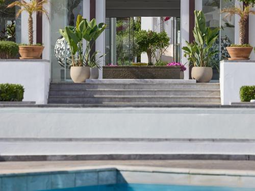 a house with potted plants on the stairs and a swimming pool at Grecotel Creta Palace in Rethymno Town