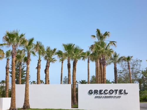 a sign in front of palm trees at Grecotel Creta Palace in Rethymno Town