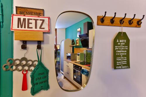 a mirror hanging on a wall next to a kitchen at Le Clos de Léa Wifi Metz Centre Ville in Metz