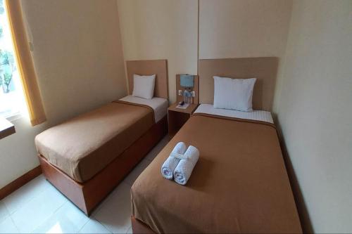 two beds in a hotel room with towels on them at OYO 94715 Homestay Kembar Syariah in Sragen