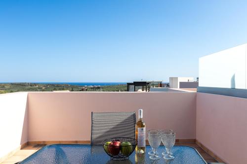 a table with a bottle of wine and glasses on a balcony at Sophias View in Loutra