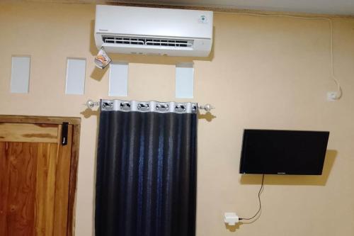 a room with a heater and a curtain and a television at OYO 94714 Khayla Homestay Syariah in Yogyakarta
