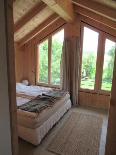 Un dormitorio con una cama en una habitación con ventanas. en Ferienhaus Remise, en Seehausen am Staffelsee