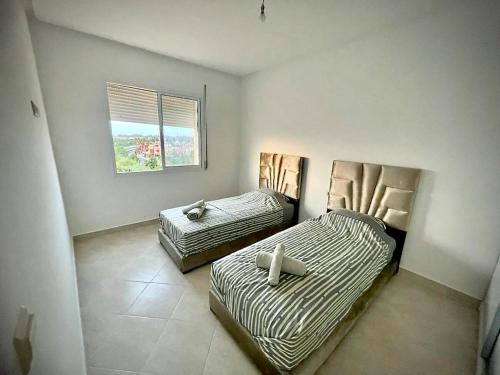 a bedroom with two beds and a window at Appartement 2 chambres en ville in Saidia 