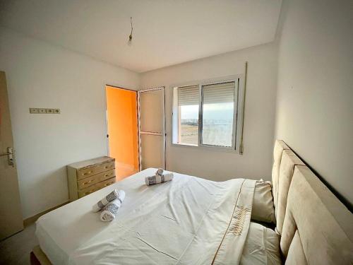 a bedroom with a large white bed and a window at Appartement 2 chambres en ville in Saidia 