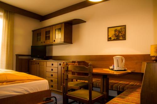a bedroom with a bed and a table and a kitchen at Hotel Carlone in Breguzzo