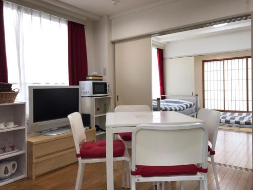 a living room with a table and chairs and a television at TOKYOtomo in Wada