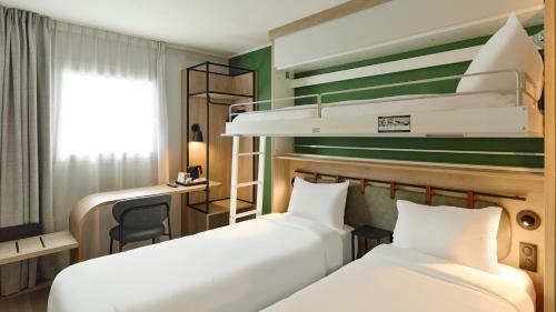 two beds in a hotel room with a desk and a bunk bed at Campanile Prime - Argenteuil in Argenteuil