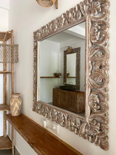 a large mirror on a wall with a wooden shelf at Iru Maldives in Thulusdhoo