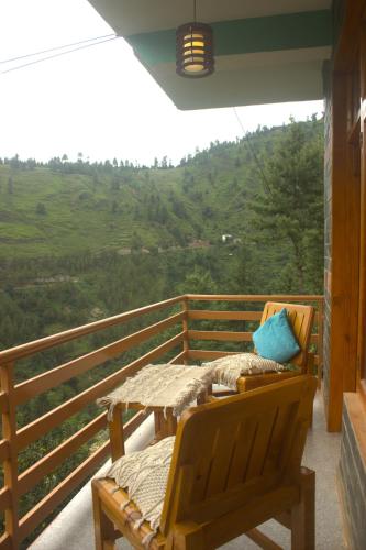 a porch with a table and a bench on a balcony at Khaapus Home Naggar in Kāndi
