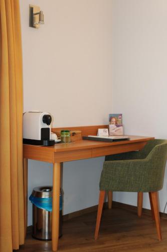 a wooden desk with a toaster and a chair at Vivea Hotel Bad Goisern in Bad Goisern