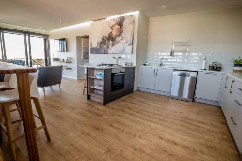 a large kitchen with white cabinets and a wooden floor at Escape to Pringle in Pringle Bay