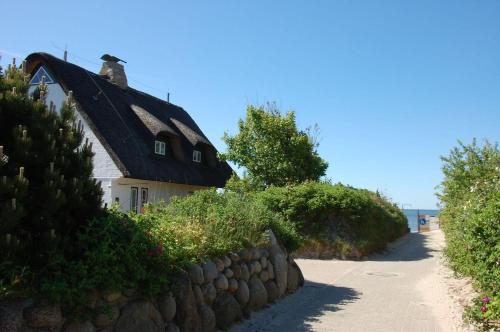 a house with a black roof next to a stone wall at Reethaus-am-Strand in Südstrand